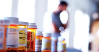 Close up of pill bottles with a blurry person in the background