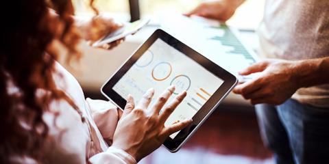 Photograph of a woman holding a tablet with data